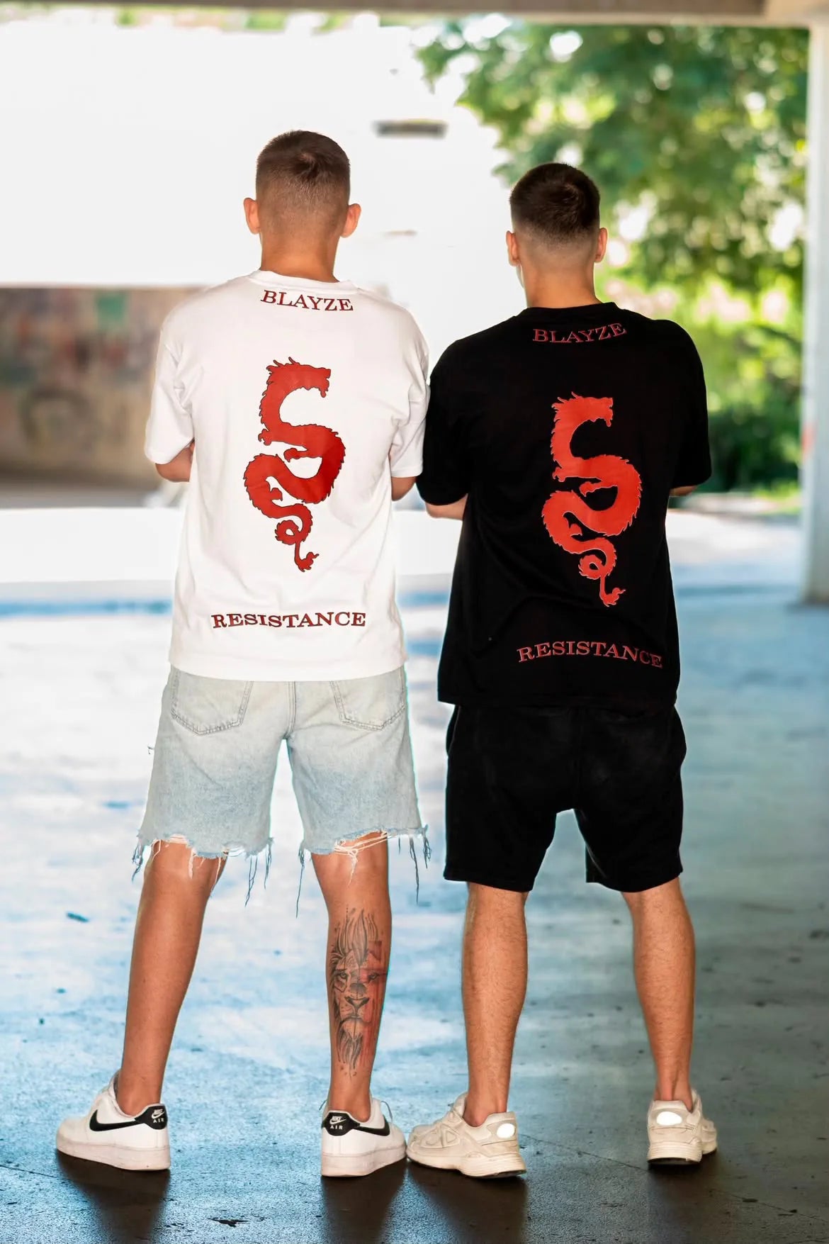 Two models wearing the Resistance dragon tee, in white and in black